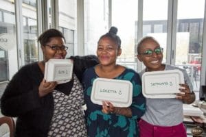 three woman smiling at the camera holding biodegradable takeaway containers