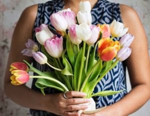 cropped photo of a woman holding a big bunch of flowers in front of her