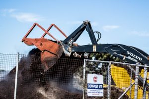 A forklift machine turning a large compost pile